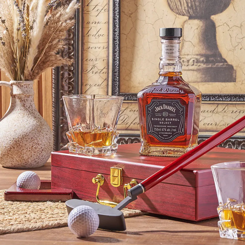 Whiskey bottle, glass, golf club, and golf balls arranged as a themed Rhode Island gift basket display.